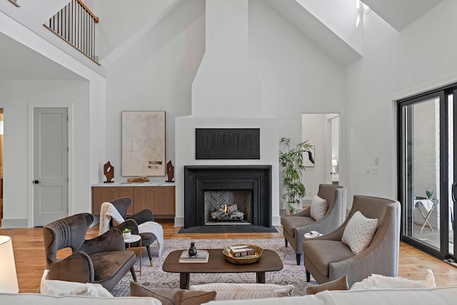 living room with light wood-style flooring, high vaulted ceiling, and a fireplace