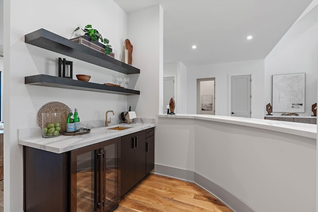 bar featuring a sink, beverage cooler, indoor wet bar, light wood finished floors, and recessed lighting
