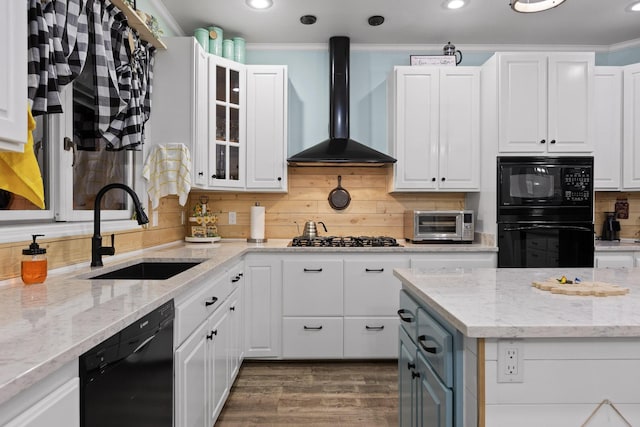 kitchen with glass insert cabinets, white cabinets, black appliances, wall chimney exhaust hood, and a sink