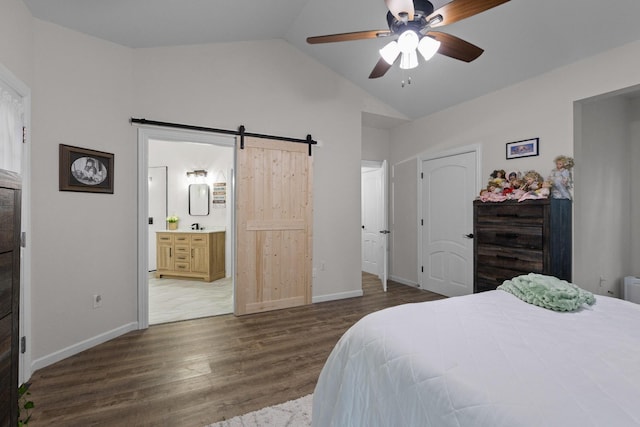 bedroom featuring wood finished floors, baseboards, vaulted ceiling, and a barn door