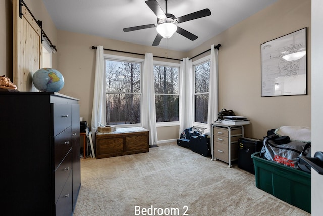 interior space featuring light carpet, ceiling fan, and a barn door
