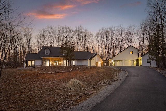 rustic home featuring driveway, a garage, and an outdoor structure