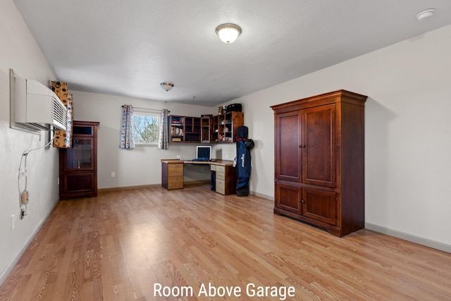 unfurnished office featuring built in study area, light wood finished floors, and baseboards