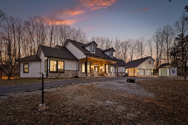 view of front of house with a porch, a detached garage, and stone siding