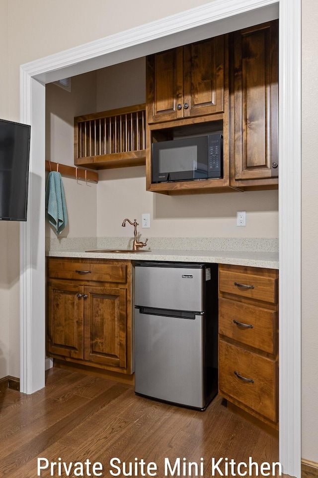 kitchen with freestanding refrigerator, black microwave, open shelves, a sink, and dark wood-style floors