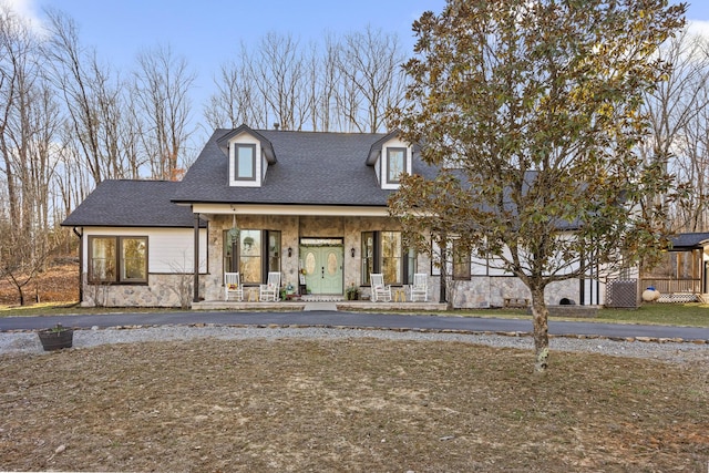 view of front of house with a porch, a shingled roof, and stone siding