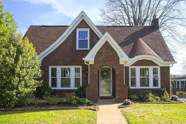 437 E College St, Pulaski, TN 38478 - english style home featuring brick siding, a front yard, a shingled roof, and a chimney