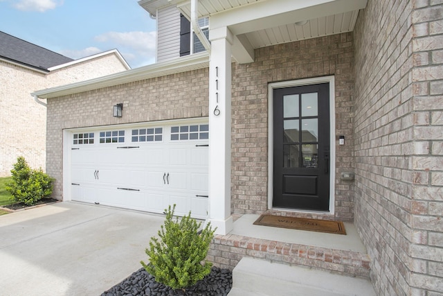 view of exterior entry featuring brick siding and driveway