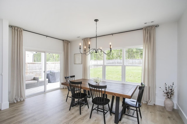 dining room featuring light wood-style flooring, visible vents, and an inviting chandelier