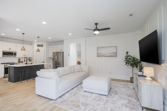 living area featuring ceiling fan, light wood-type flooring, visible vents, and recessed lighting