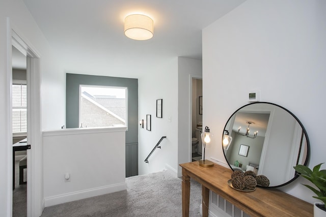 hall with baseboards, carpet floors, an upstairs landing, and a healthy amount of sunlight