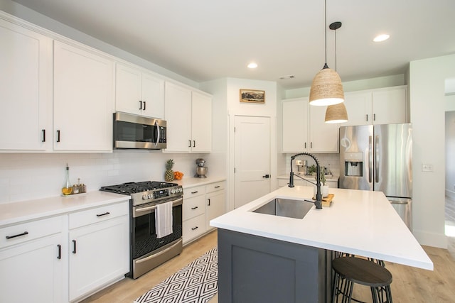 kitchen featuring tasteful backsplash, a sink, light wood-style floors, stainless steel appliances, and white cabinetry
