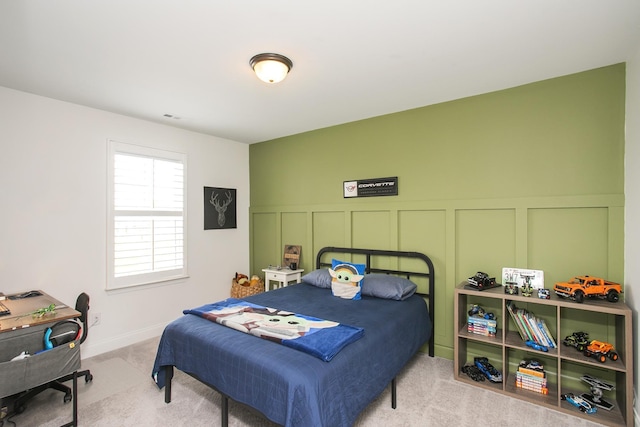 carpeted bedroom featuring wainscoting, a decorative wall, and visible vents