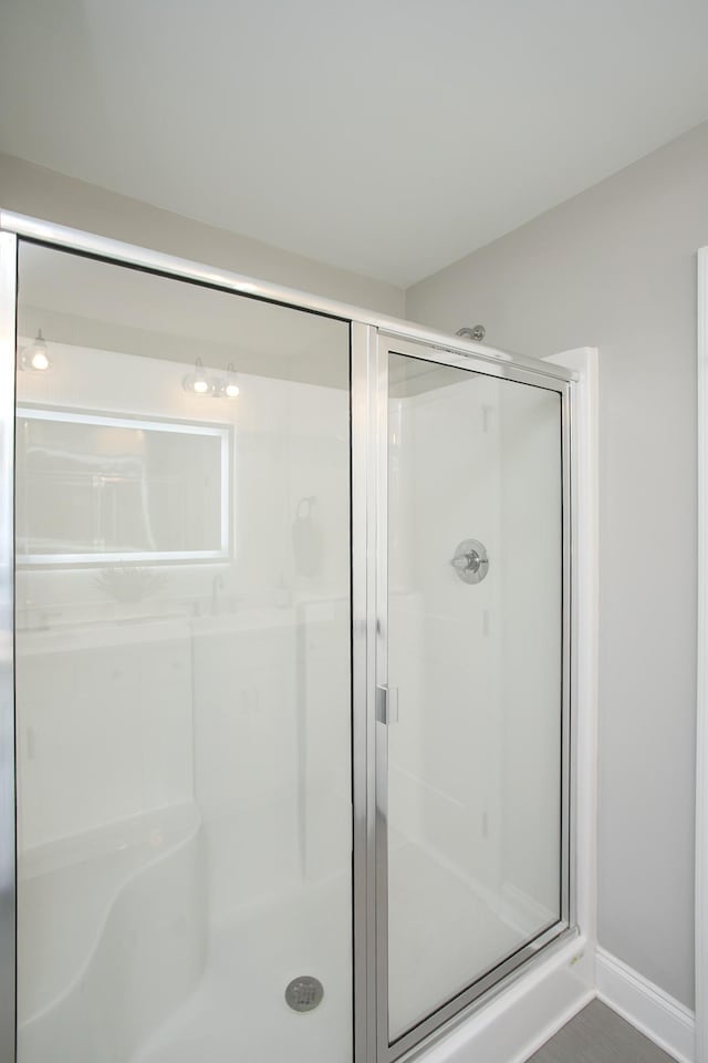 bathroom featuring a shower stall and baseboards