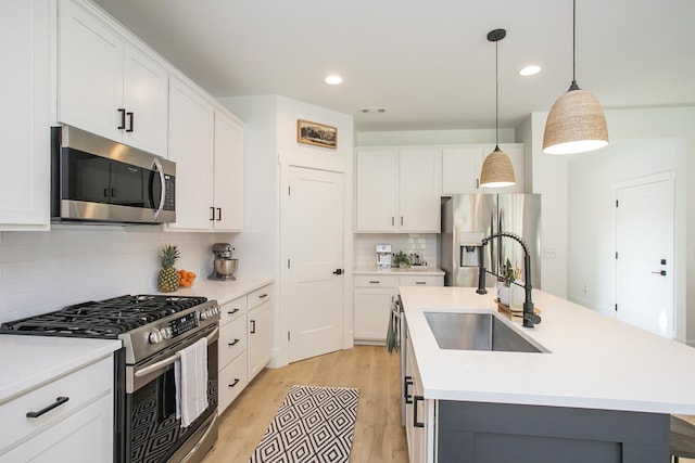 kitchen featuring tasteful backsplash, a sink, a center island with sink, light countertops, and appliances with stainless steel finishes