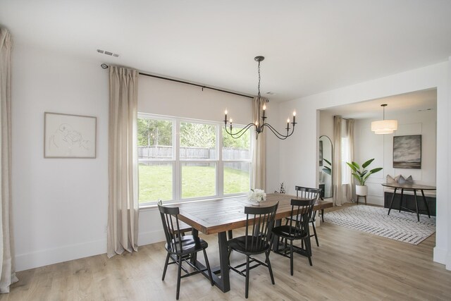 dining area with a notable chandelier, baseboards, visible vents, and light wood-style floors