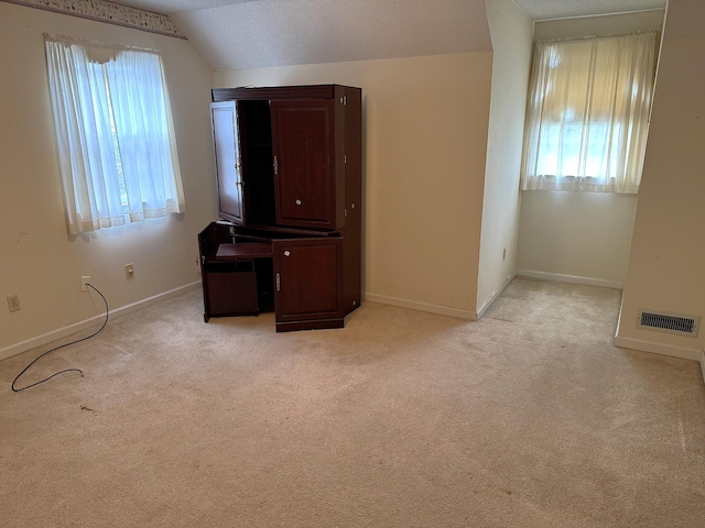 unfurnished bedroom featuring visible vents, baseboards, vaulted ceiling, and light carpet