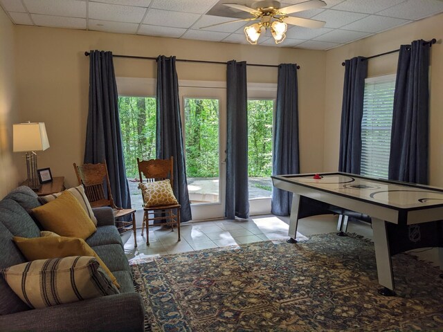 rec room with tile patterned flooring, a drop ceiling, and a ceiling fan