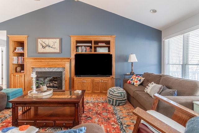 living area with a high end fireplace and vaulted ceiling