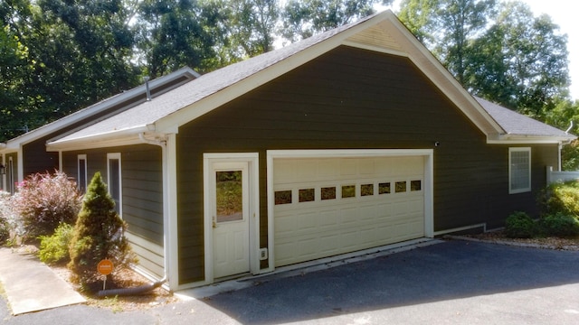 exterior space with roof with shingles and a garage