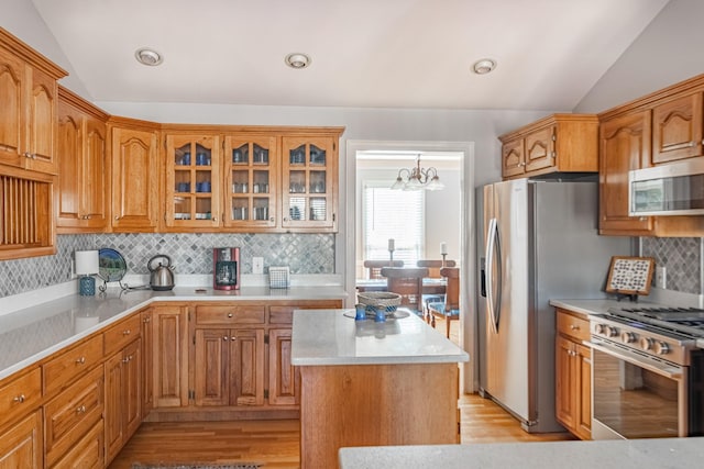 kitchen with glass insert cabinets, light countertops, light wood-style floors, stainless steel appliances, and lofted ceiling