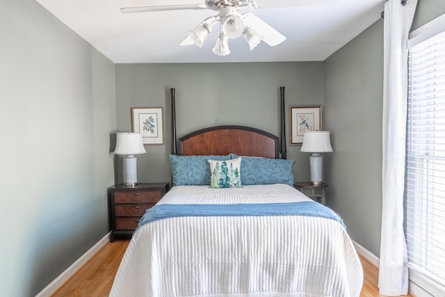 bedroom with light wood finished floors, baseboards, and ceiling fan