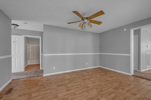1425 Wesley Rd, Bon Aqua, TN 37025 - unfurnished room with visible vents, baseboards, ceiling fan, wainscoting, and light wood-style flooring