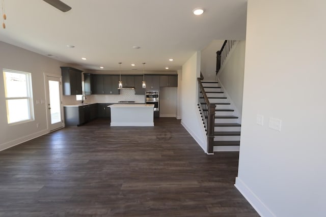 kitchen featuring baseboards, ventilation hood, light countertops, recessed lighting, and a kitchen island