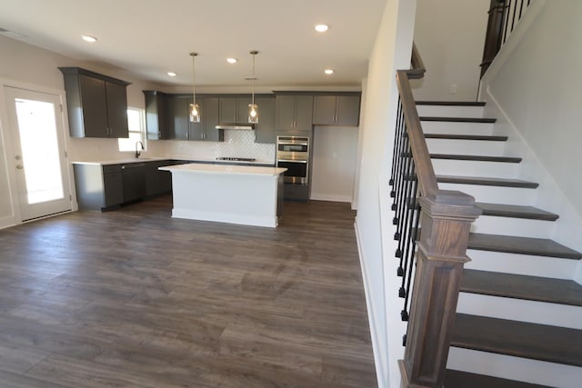 kitchen with a sink, cooktop, light countertops, under cabinet range hood, and recessed lighting