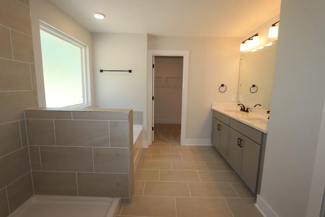 bathroom featuring a sink, a spacious closet, double vanity, baseboards, and tile patterned flooring