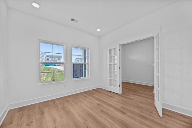 unfurnished room featuring light wood finished floors, baseboards, and french doors