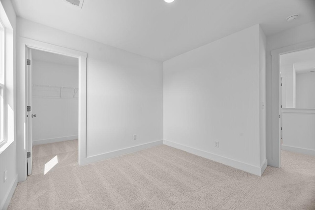 unfurnished bedroom featuring baseboards, carpet flooring, a spacious closet, and a closet