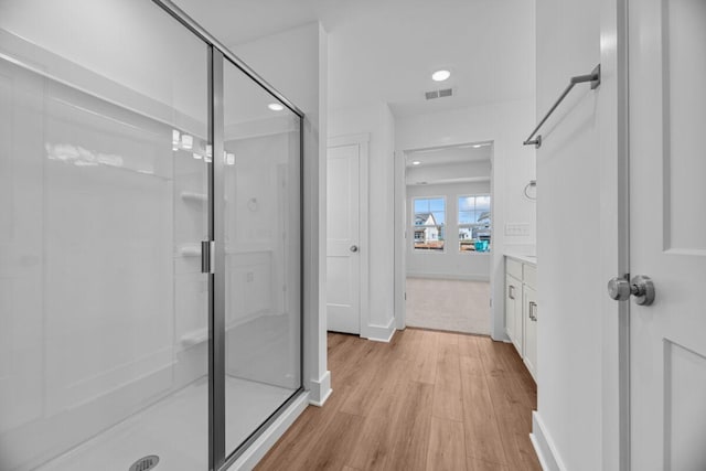 bathroom featuring wood finished floors, a stall shower, baseboards, visible vents, and recessed lighting