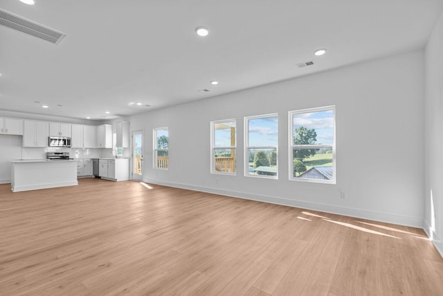 unfurnished living room with recessed lighting, visible vents, light wood finished floors, and baseboards