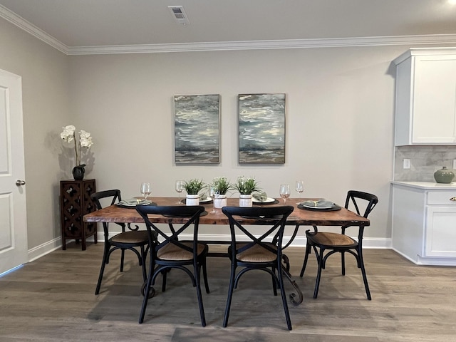 dining space with crown molding, wood finished floors, baseboards, and visible vents