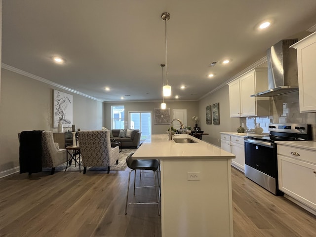 kitchen featuring stainless steel range with electric stovetop, wall chimney exhaust hood, a sink, and ornamental molding