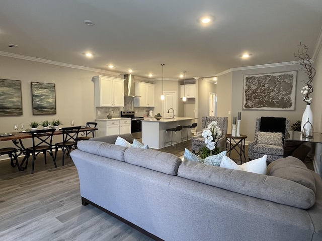 living area with crown molding, light wood finished floors, visible vents, and recessed lighting
