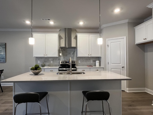 kitchen with a sink, wall chimney range hood, ornamental molding, and visible vents
