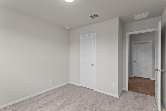 unfurnished bedroom featuring baseboards, visible vents, and carpet