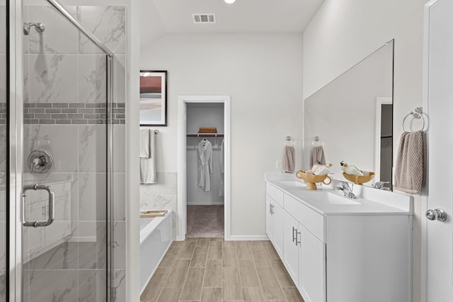 bathroom featuring a walk in closet, a sink, visible vents, and a stall shower