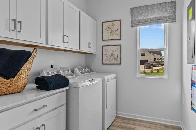 washroom featuring light wood-style flooring, baseboards, cabinet space, and washing machine and dryer