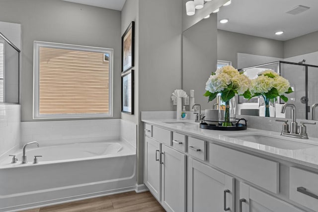 bathroom featuring a bath, a sink, a stall shower, and wood finished floors