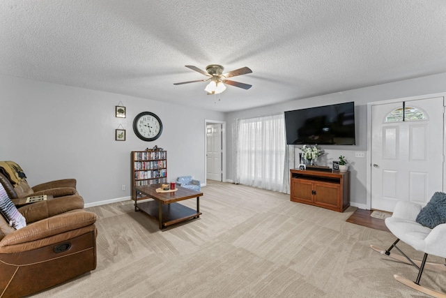 living area featuring plenty of natural light, a ceiling fan, baseboards, and light colored carpet