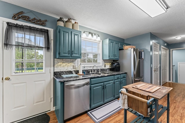 kitchen featuring dark countertops, appliances with stainless steel finishes, blue cabinetry, and a textured ceiling