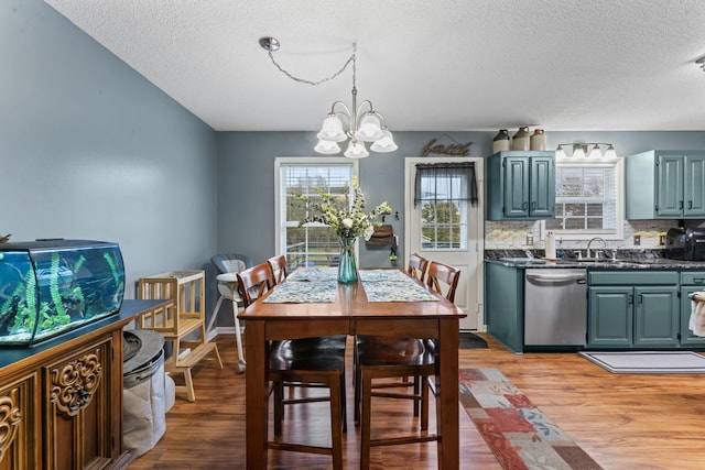 dining area with an inviting chandelier, light wood-type flooring, and a textured ceiling