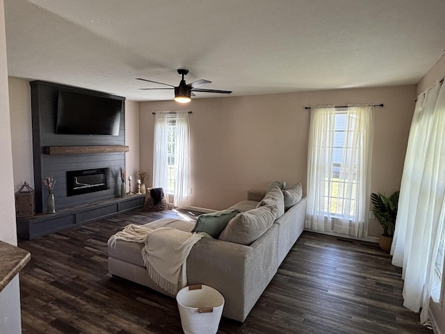living area with a wealth of natural light, ceiling fan, and dark wood-style floors