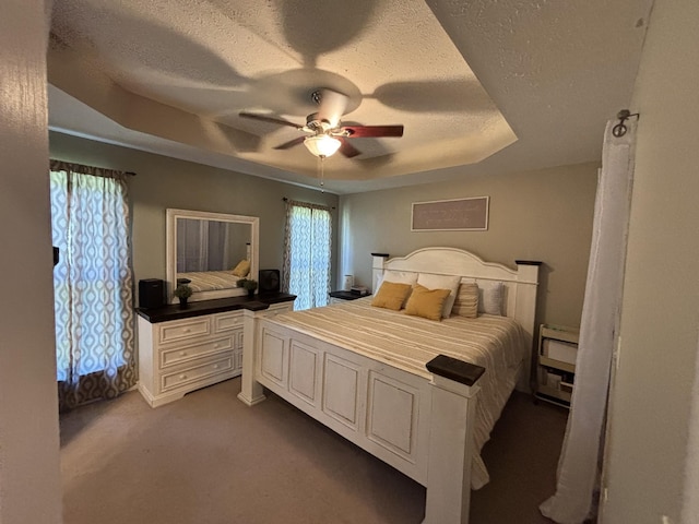 carpeted bedroom featuring a tray ceiling, a textured ceiling, and ceiling fan
