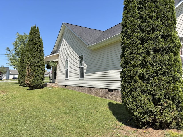 view of side of property with a yard, crawl space, and a shingled roof