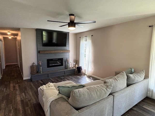 living area with a large fireplace, baseboards, a ceiling fan, and wood finished floors