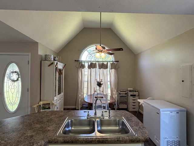 kitchen with a healthy amount of sunlight, a sink, fridge, and vaulted ceiling